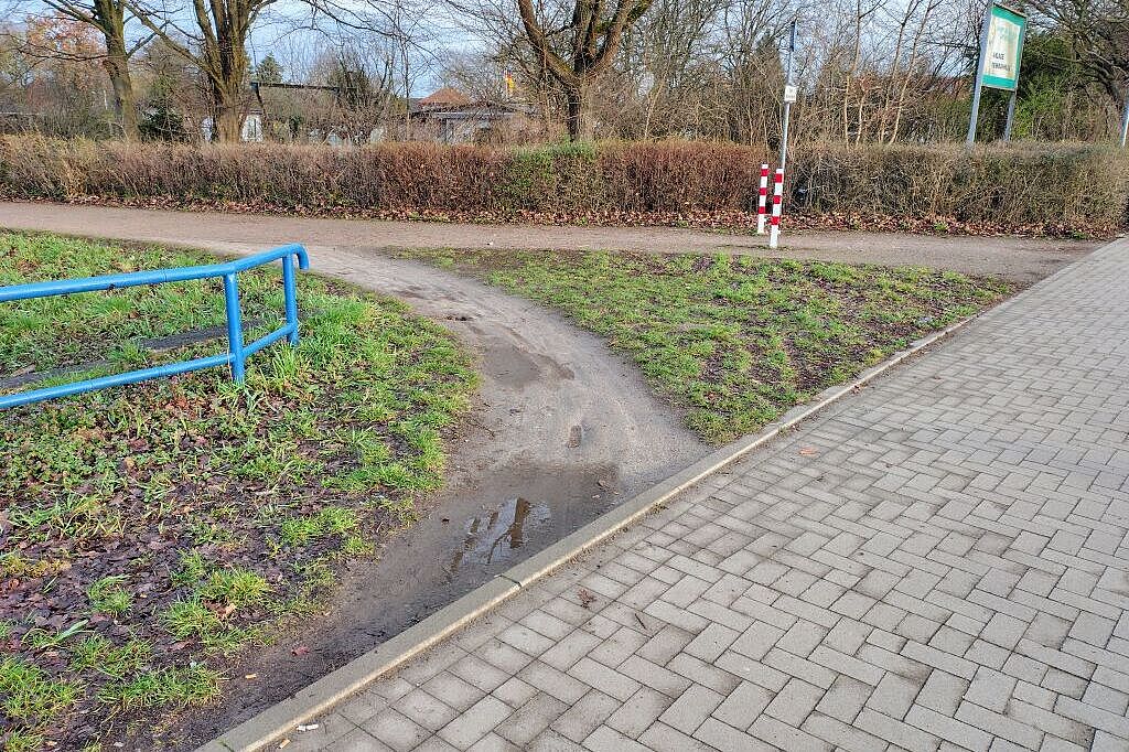 VERBESSERUNGSVORSCHLAG. - Hintergrund: ALLE beobachteten Fußgänger und ALLE beobachteten Radfahrenden nutzten diese unbefestigten Pfad. Grund: Die befestigte Wegführung liegt von der tatsächlich sinnvollen Wegführung nicht nur zu weit weg, sondern ist auch wegen der rechtwinkligen Einmündung und der beschränkten / gefährlich reduzierten Sicht auf den Radweg entlang der Theodor-Heuss-Straße kaum sicher befahrbar. - Maßnahmen-Vorschlag des ＡＤＦＣ Langenhagen: Befestigung dieser Abbiegespur in ähnlicher Art wie den Weg, um häufig gegangene / gefahrene Wege durch Pfützen / durch Schlamm zu vermeiden. Und deren Gefährlichkeit.
