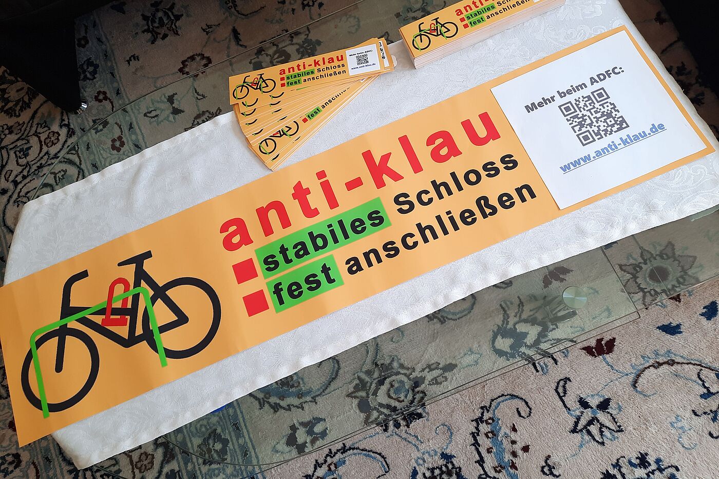 Das GROßE anti-klau-Plakat liegt fertig auf dem Vorbereitungstisch: Oben zwei Stapel mit den Aufklebern, die im öffentlich zugänglichen Stadtgebiet an Fahrradbügeln aufgeklebt werden / bereits aufgeklebt wurden.