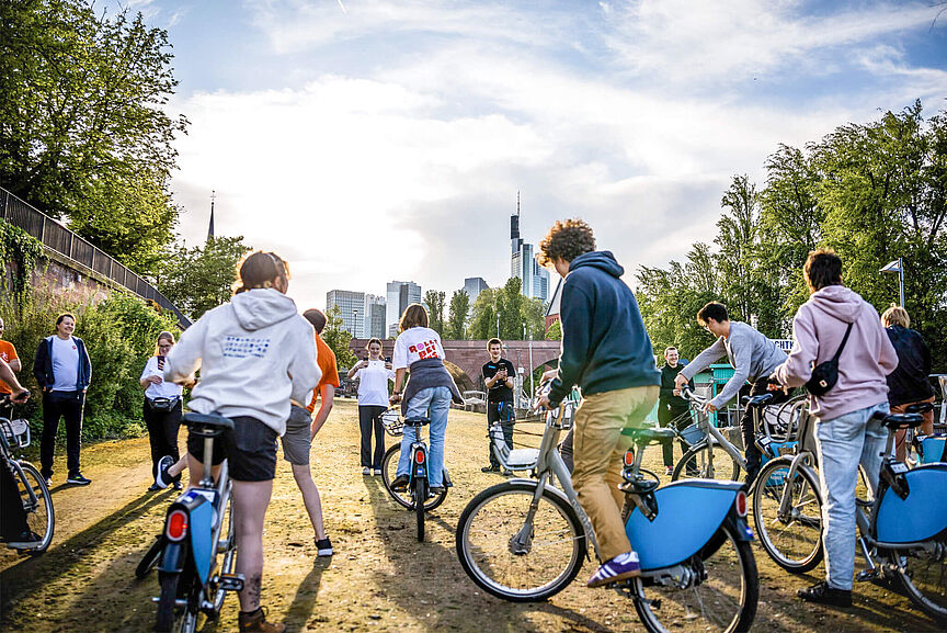 Junger ADFC Junge Menschen fahren auf Leihfahrrädern auf einem Weg im Freien.
