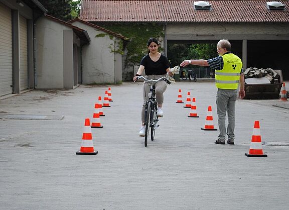Frau fährt mit Fahrrad und nimmt Tuch von Lehrer entgegen