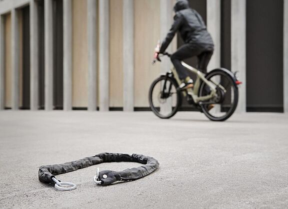 Fahrradfahrer fährt an einem Fahrradschloss vorbei, das auf dem Boden liegt.